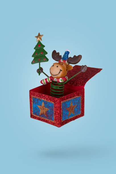 可爱的驯鹿在一个圣诞礼品盒孤立在蓝色背景。图片下载
