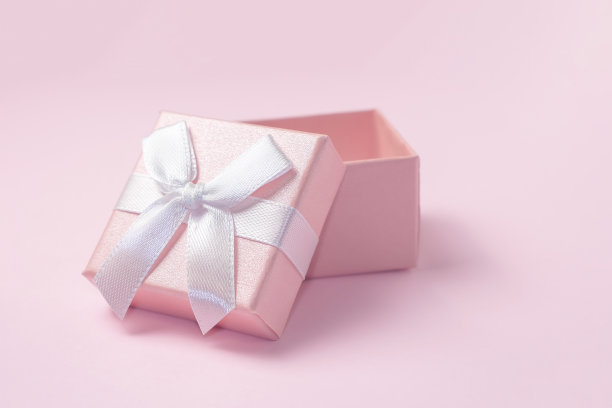 粉红色的礼品盒上有一个白色的蝴蝶结。打开粉红色背景的礼品盒图片下载