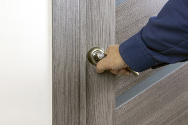 男人的手打开了门把手后面的灰色经典门。图片下载