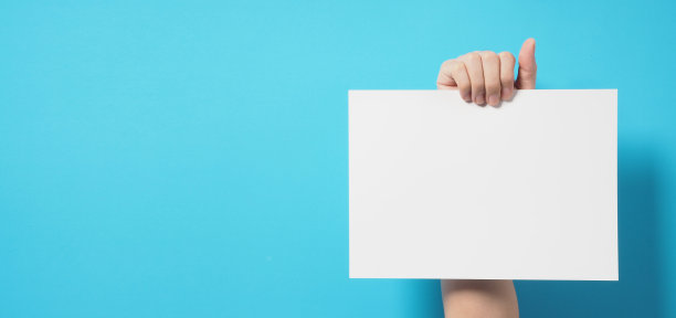 一只手拿着蓝色背景的白色A4纸。图片下载