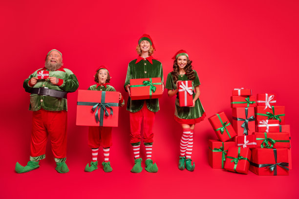 圣诞老人工人的全身照片不同的高度站着礼品盒，穿着新年服装孤立在红色背景图片下载