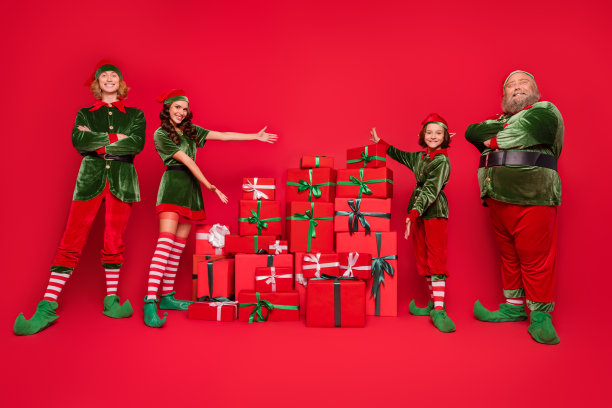 圣诞老人助手的全长照片，人们索引礼盒穿着小精灵的衣服孤立在红色的背景图片下载