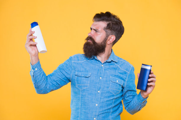 提供个人护理的治疗。嬉皮士拿着黄色背景的洗发水和护发素。头发治疗。洗发水和护发素。胡子治疗产品。皮肤治疗。护肤品图片下载