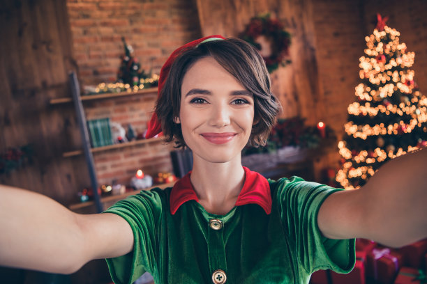 年轻积极的圣诞老人帮手女人圣诞节的照片，在屋里，在家里，拿着相机自拍圣诞节图片下载