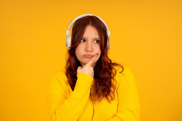 女人带着沉思的表情，戴着耳机听音乐。图片下载