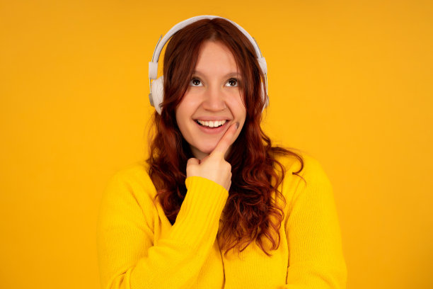 女人带着沉思的表情，戴着耳机听音乐。图片下载