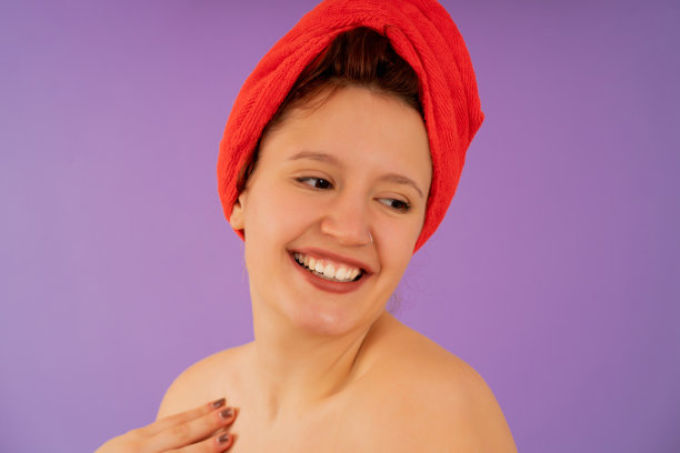 年轻女子头戴毛巾面带微笑。图片下载