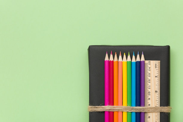 五颜六色的学校和办公室用品——黑色的书和浅绿色的背景上的铅笔和尺子。顶部视图与复制空间。图片下载