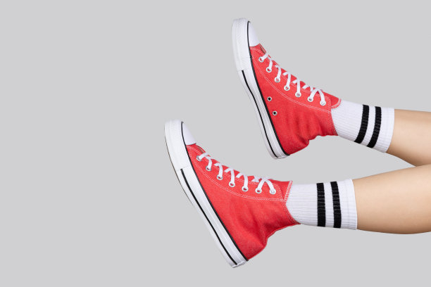 女性的腿在时尚的红色运动鞋和白色袜子的灰色背景图片下载