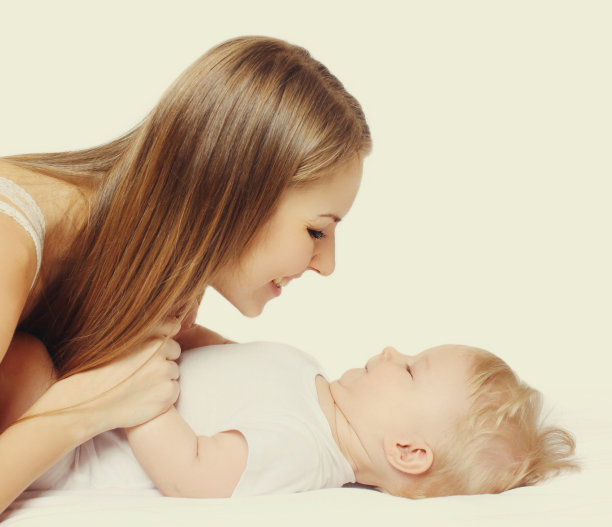 在白色的背景上，快乐微笑的母亲和婴儿一起玩耍的特写图片下载