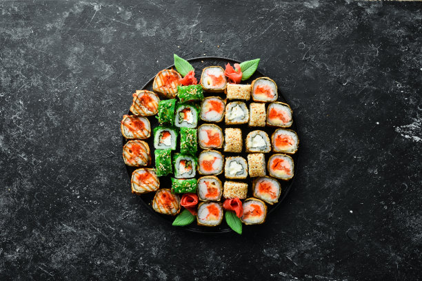 寿司店的菜单上。一套彩色美味的寿司卷在黑色盘子。前视图。图片下载