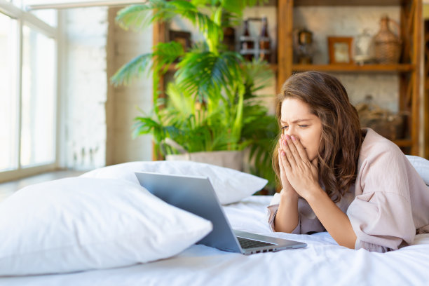一张焦虑的成年女性躺在床上的笔记本电脑显示器前的照片图片下载