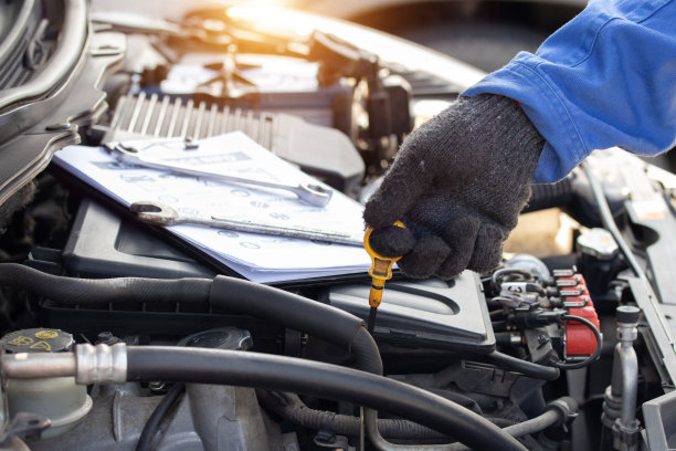 机械师在他的车库工作，汽车检查和汽车服务店的概念。在车间的车库，靠近手动机械师检查发动机的油位。图片下载