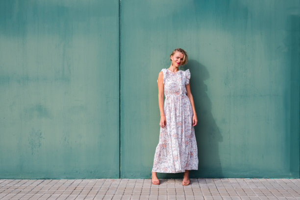 漂亮的金发白种人，穿着夏装，倚在绿色的墙上图片下载
