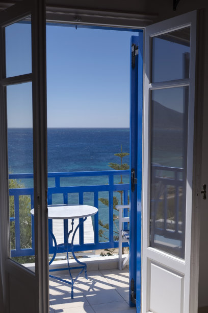 希腊阳台的窗户面向海景。典型的小桌子，白色和蓝色。照片摄于Koufonisia岛。希腊图片下载