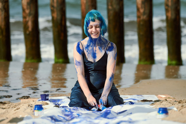 蓝色头发的艺术女性行为艺术家，穿着衣服，涂着蓝色水粉画在她的身体图片下载