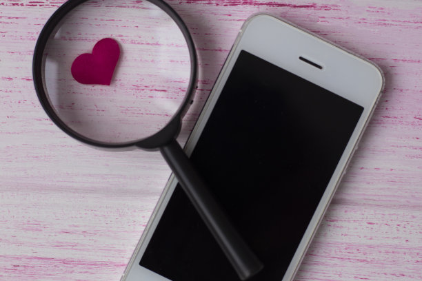 心脏在放大镜下靠近手机。图片下载