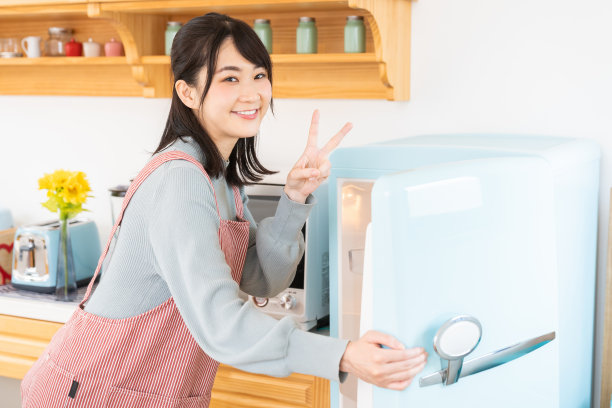 漂亮的亚洲女人在厨房做饭，冰箱图片下载
