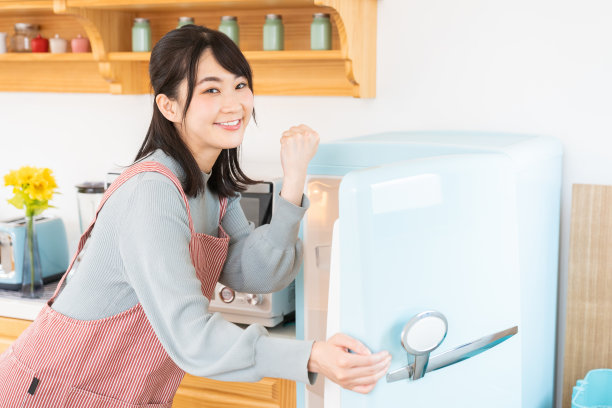 漂亮的亚洲女人在厨房做饭，冰箱图片下载