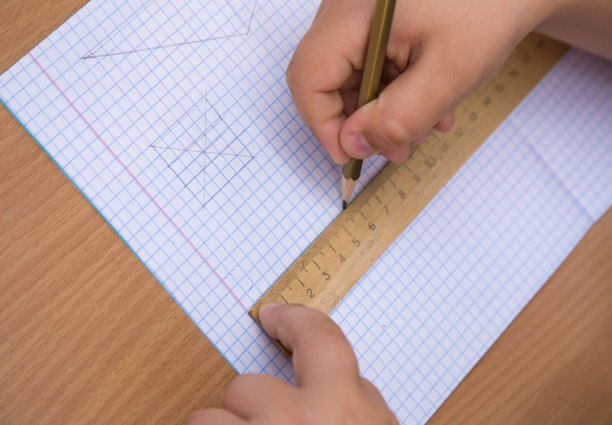 学生用铅笔沿着尺子在笔记本上画一条直线。图片下载