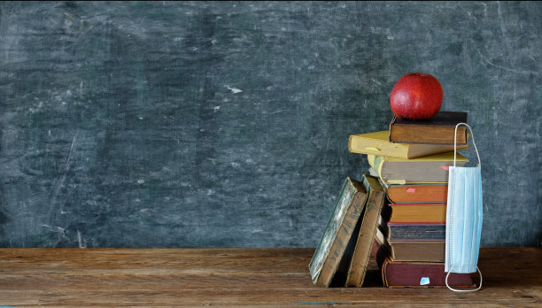 在电晕时代回到学校，书堆，苹果和电晕面具在学校黑板前，免费复印空间图片下载