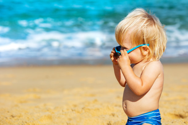 沙滩上戴着太阳镜的小男孩图片下载