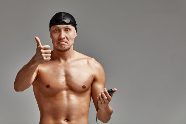 兴奋的游泳者与秒表站在灰色的背景。新纪录。动机，广告横幅，文字位置图片下载