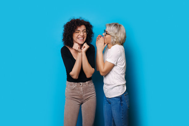 可爱的卷发女人在做惊讶的手势，而金发妹妹在低语着什么图片下载