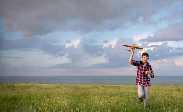 男孩在秋天日落时将飞机发射到天空中。一个少年梦想成为飞行员。在自然中积极的娱乐观念。图片下载