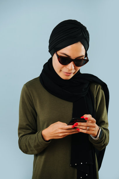 穆斯林妇女戴着墨镜在手机上发短信图片下载