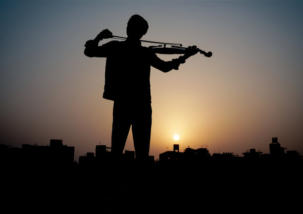 音乐家演奏小提琴。音乐和音色概念。男性音乐家的剪影图像图片下载