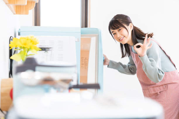 漂亮的亚洲女人在厨房做饭，冰箱图片下载