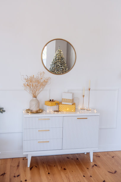 现代的床头柜上摆放着黄色、金色的礼品盒。花瓶里有干花，圣诞树图片下载