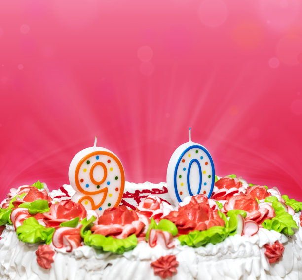 生日蛋糕，装饰着彩灯和蜡烛，数字9和0。乔布斯90年的经历在粉红色的背景上，有文字的地方。副本的空间图片下载