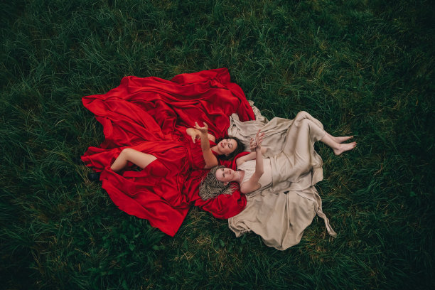 两个穿着长裙躺在草地上的漂亮女人的时尚照片图片下载
