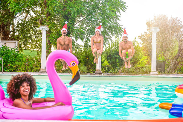 Happy friends with christmas hat Jumping Into swimming pool at a holiday resort - multi - ethnic young having fun on christmas holidays - Travel, holidays, christmas lifestyle concept .带着圣诞帽的快乐朋友跳进度假胜地的游泳池图片下载