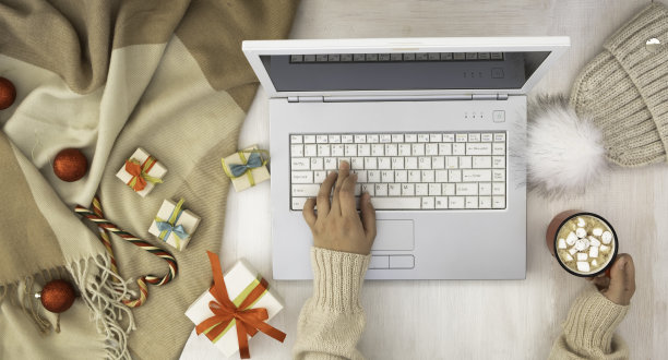 女孩的手放在笔记本电脑键盘上。圣诞布置，笔记本电脑，礼物和装饰。图片下载