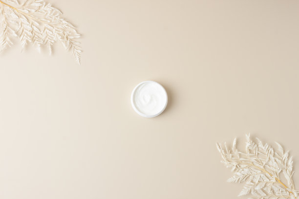 淡米色背景上有花的化妆霜。平铺，复制空间图片下载