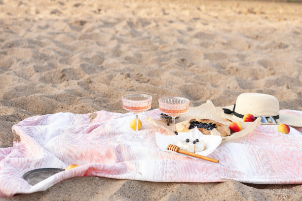 美丽的夏日野餐在日落的海滩上与玫瑰酒，奶酪，蓝莓果酱和新鲜水果。本空间图片下载