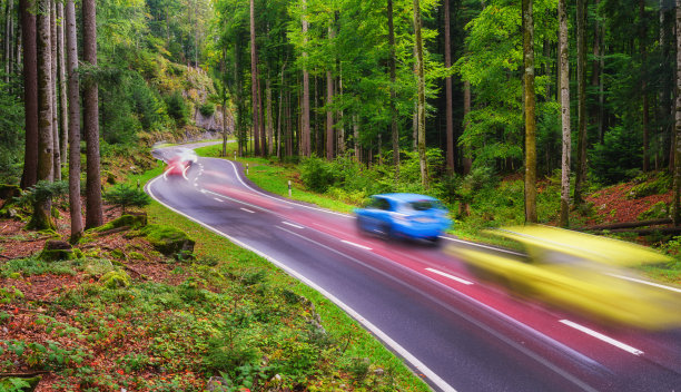 森林中的一条路。快速交通。模糊的车灯。傍晚的风景。大分辨率照片设计。图片下载