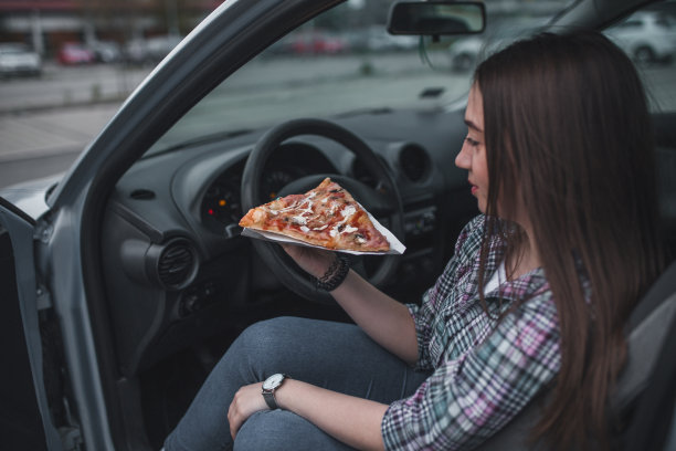 年轻女子在车里吃披萨图片下载