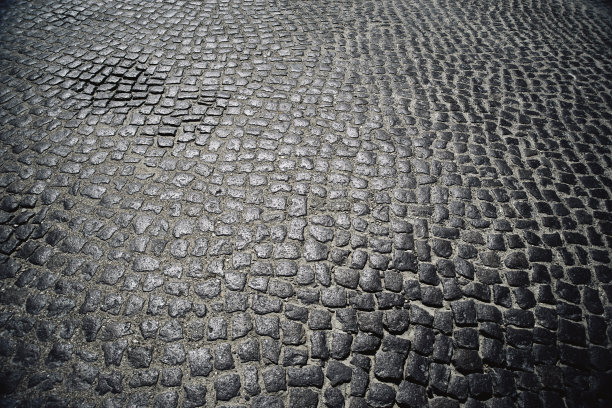 抽象的深色背景，粗糙的旧花岗岩铺路石与光的反射图片下载