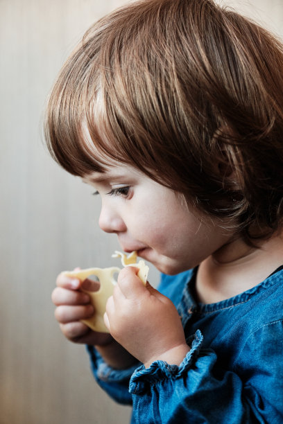 小女孩在吃奶酪。小女孩在吃奶酪。可爱的宝宝享受一片奶酪图片下载
