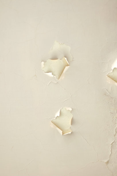 破损的旧墙，灰泥不见了。石膏和肿块。背景为家庭改建和维修需要。米色风化灰泥墙背景。天花板上米色松灰泥。改造的必要性。图片下载