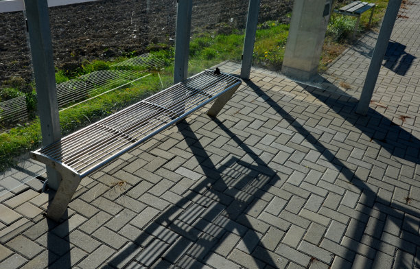 釉面城市风格的公交车站。遮蔽处的玻璃墙，带有灰色金属长凳的露台。可金属丝清洗的阀座表面。混凝土铺路块，联锁铺路图片下载