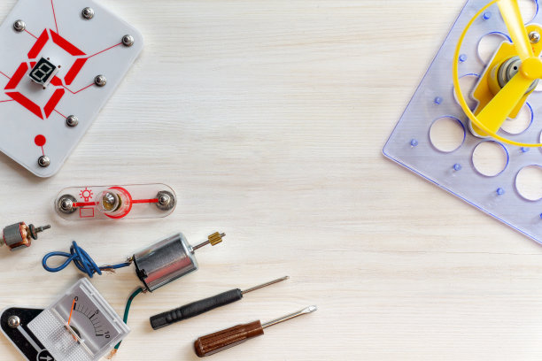 机器人学，电子产品的工具和零件的平面铺设。螺丝刀，灯泡，电池，测量仪器，白色木制背景。儿童娱乐科学概念图片下载