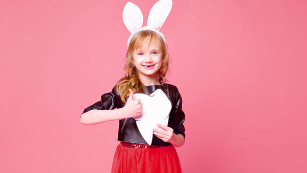 美丽的小可爱金发女孩6-7岁与牙刷和牙齿布局在粉红色的背景。健康观念，口腔卫生，人与美。房间的布局。有选择性的重点。图片下载