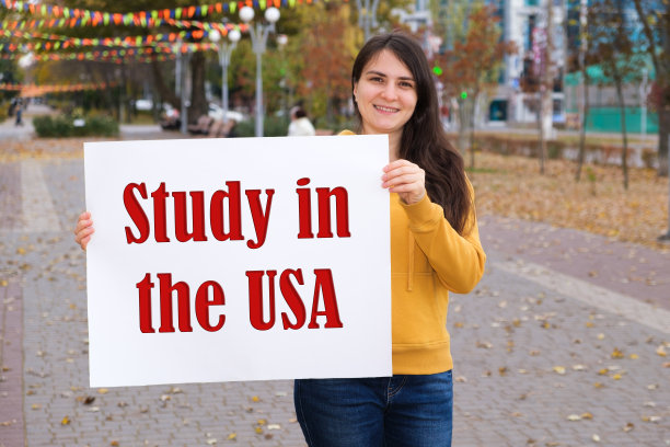 一名妇女微笑着举着一张海报，上面写着“在乌克兰学习”图片下载