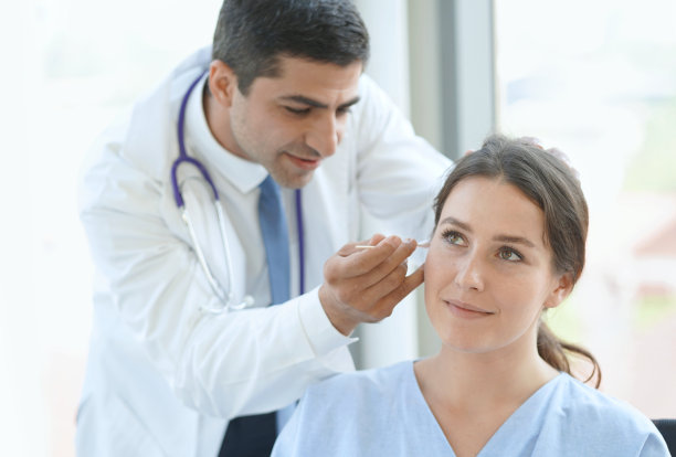 医生在体检时检查病人的耳朵。图片下载