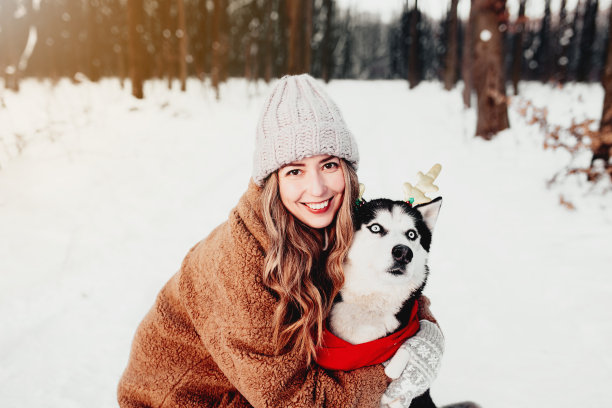 照片上的女孩和狗在冬季森林的白雪在圣诞节图片下载
